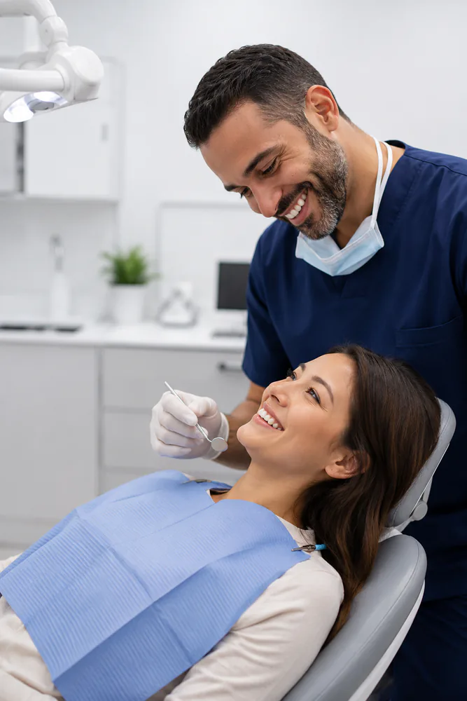 Dentist smiling while examining a patient during a dental cleaning